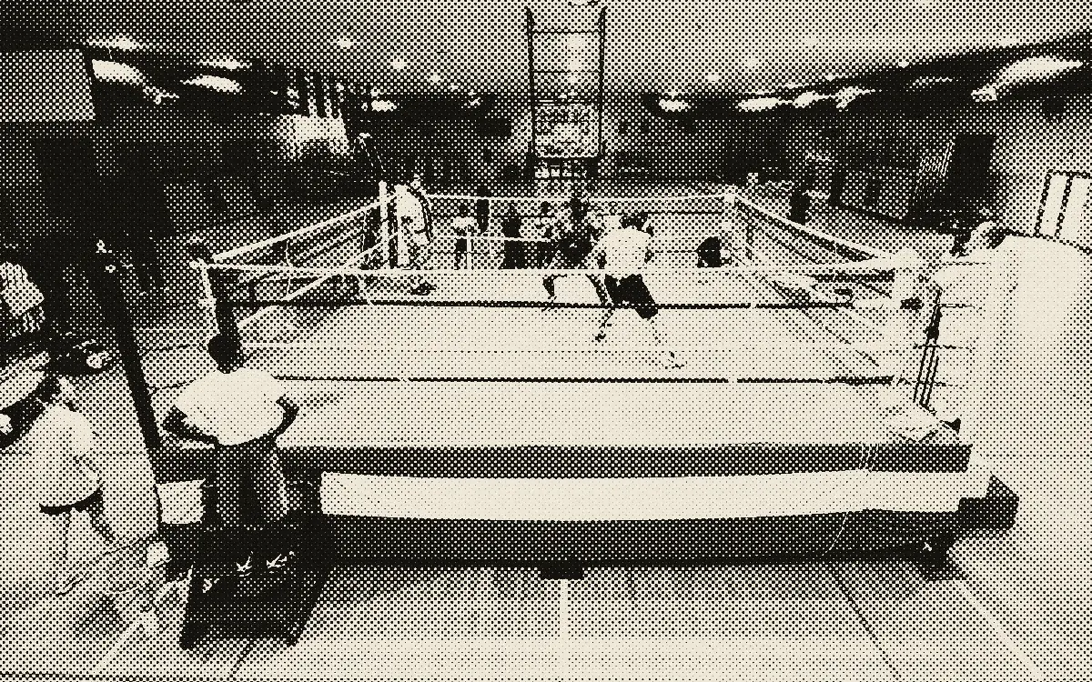 Salle d'entraînement avec un ring et des boxeurs qui s'entraînent